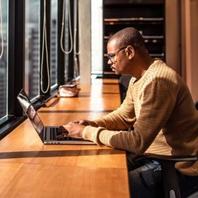 Uomo che lavora al computer accanto a una finestra