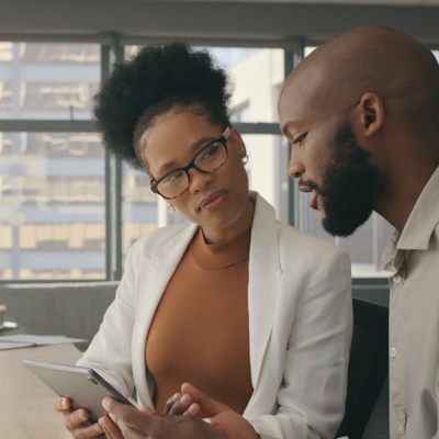 Office workers in a conference room discussing information on a tablet