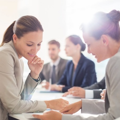 A group of professional office workers collaborating around a table in a conference room.