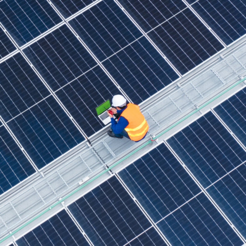 person in hard hat working on large scale solar panels