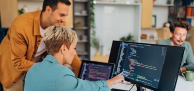 Two office workers looking at AI algorithms on a computer monitor
