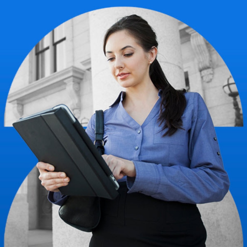 person looking at a tablet while outside a government building.