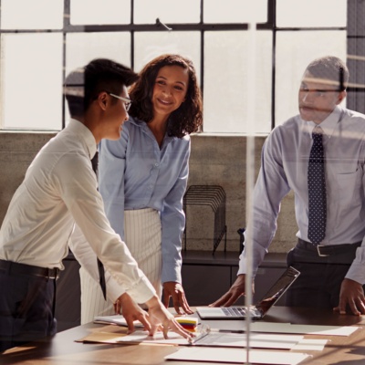 Group of colleagues standing and talking in room with windows
