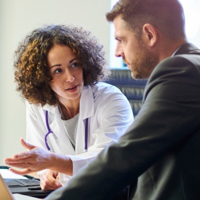 Two healthcare providers conversing in a conference room. 