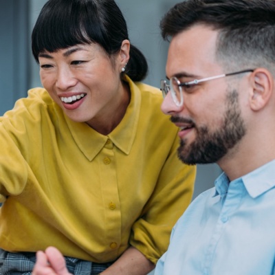 Two happy employees looking at a laptop screen together.