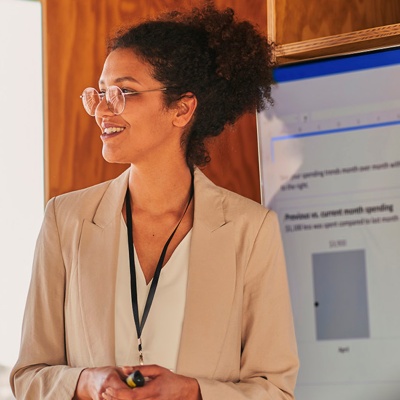 A woman wearing glasses presents data in front of a small audience