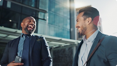 Two business men laughing and walking in city