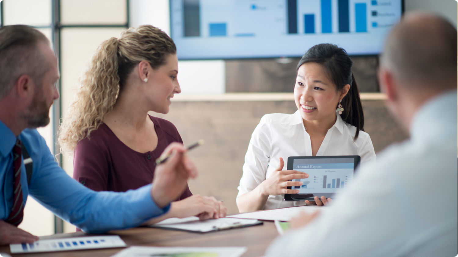 People in a meeting looking at a table with a chart.