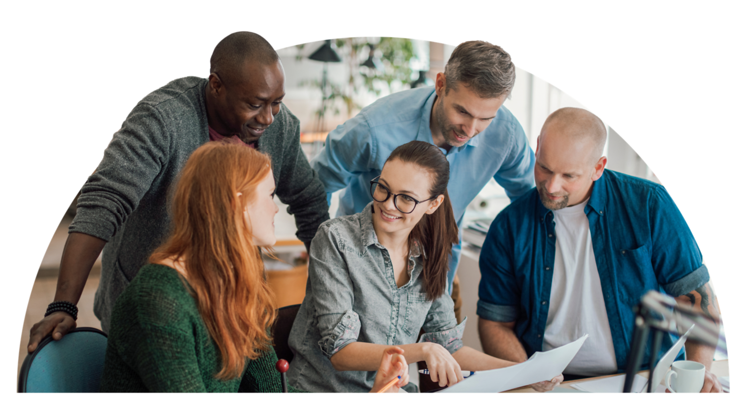 Group of people looking at paper around a table.