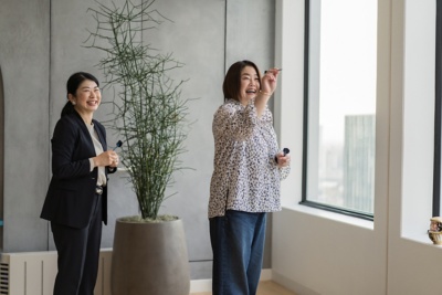 ランチの容器を持って笑いながら廊下を歩く 2 人の社員