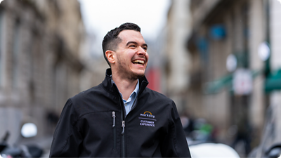 Collaborateur souriant, portant une veste Workday et regardant vers l'horizon.