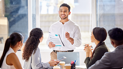 Person standing speaking to other people at a table. 