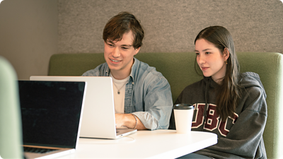 Two employees sitting together in front of a laptop.