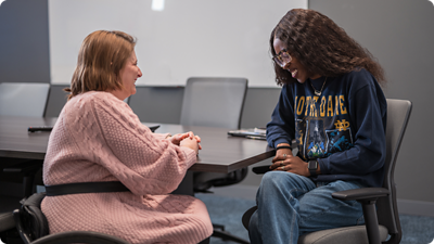 Zwei Mitarbeiterinnen, die sich im Büro unterhalten