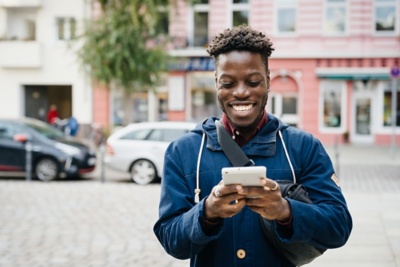 Happy person using their mobile phone on a city sidewalk