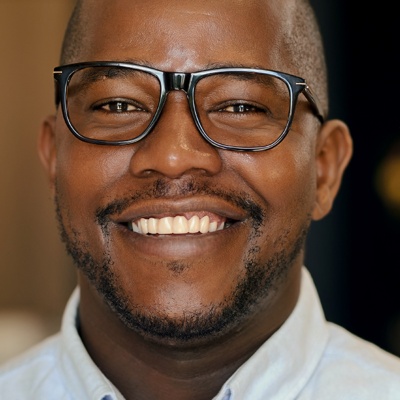 Man with glasses and button-up shirt smiling at the camera