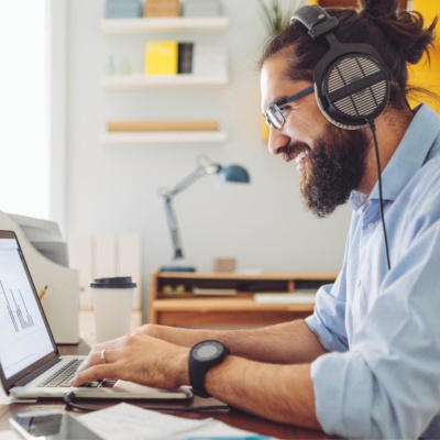 Empleado con auriculares en un escritorio con un ordenador portátil.