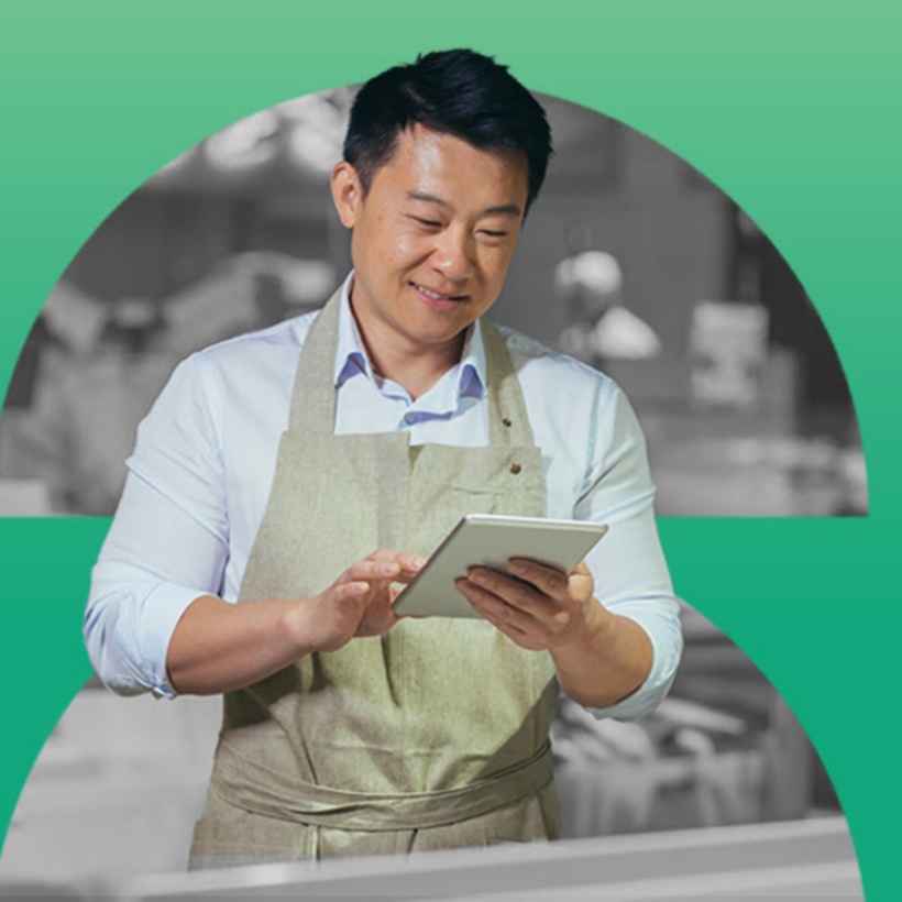 retail employee wearing an apron and looking at a tablet.