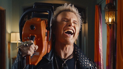 Billy Idol in Workday Superbowl ad carrying chainsaw in hotel