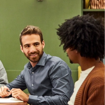 Colleagues sitting at a table in a shared workspace. 