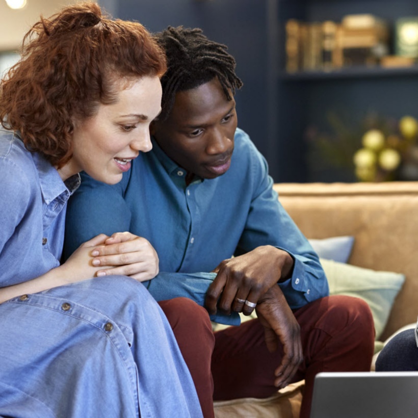 three colleagues sitting on couches looking at a tablet screen