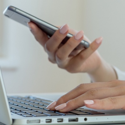 Person holding a phone while working on a laptop