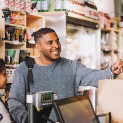 People in a grocery store checkout line talking to the clerk.