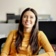 Woman in yellow shirt sitting in chair in cubicle smiling