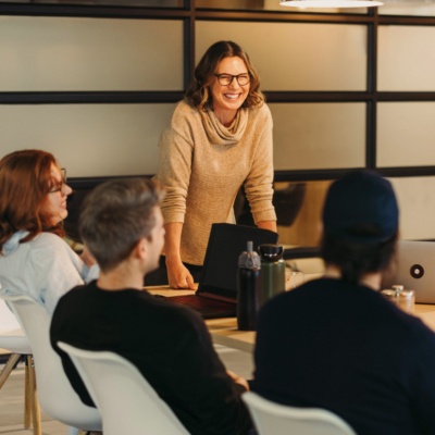 Woman standing at head of table with colleagues