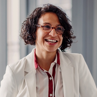 Woman with glasses smiling in conversation with coworker