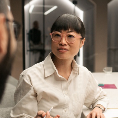 Woman with glasses talking to colleague at table
