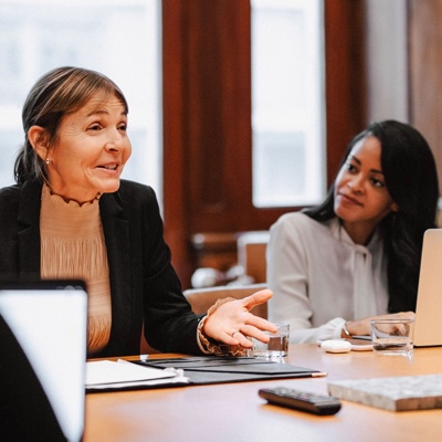 Professionally dressed women and men sitting at table in a meeting room having a conversation